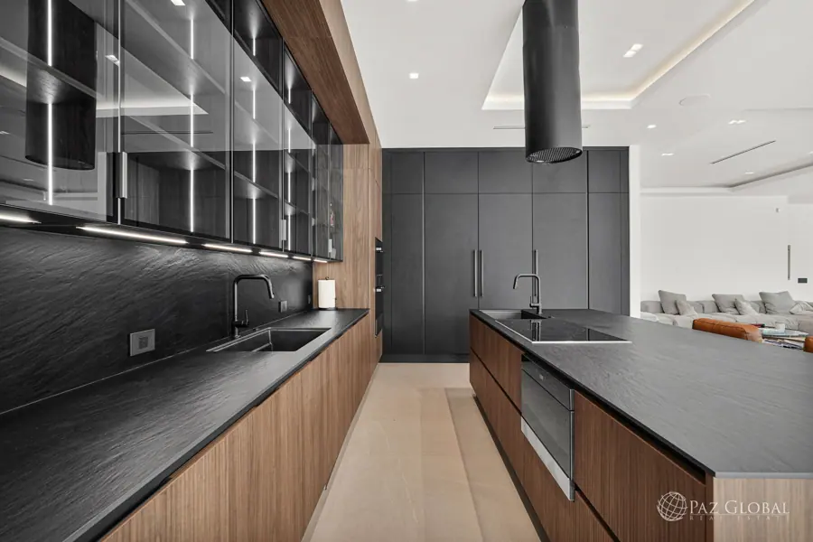 Kitchen detail with lit glass cabinets and dark stone counters
